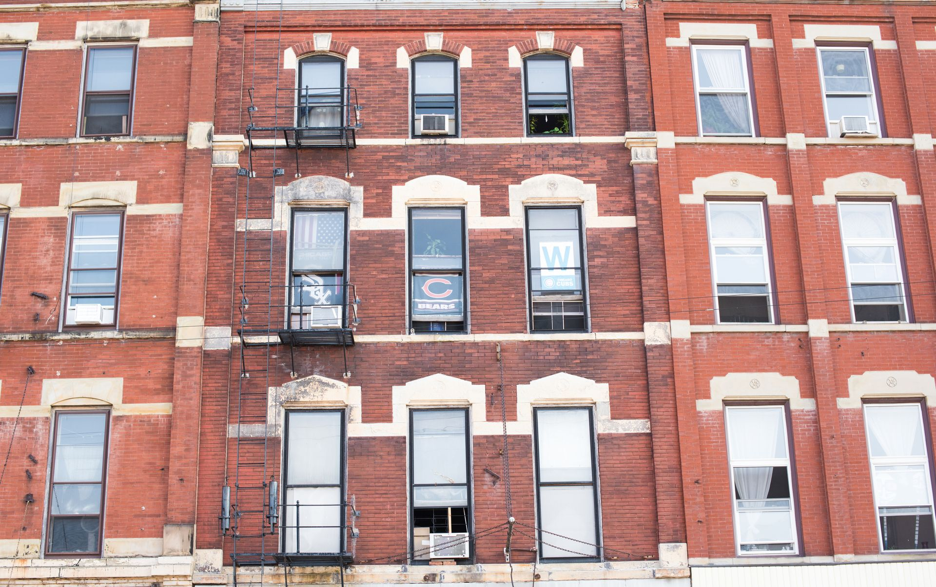 Brick apartment building facade with rows of windows and white trim