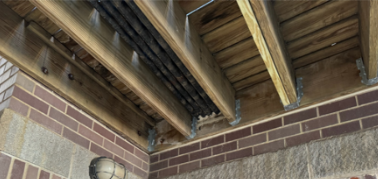 Wooden ceiling beams and ductwork inside a brick-walled building interior