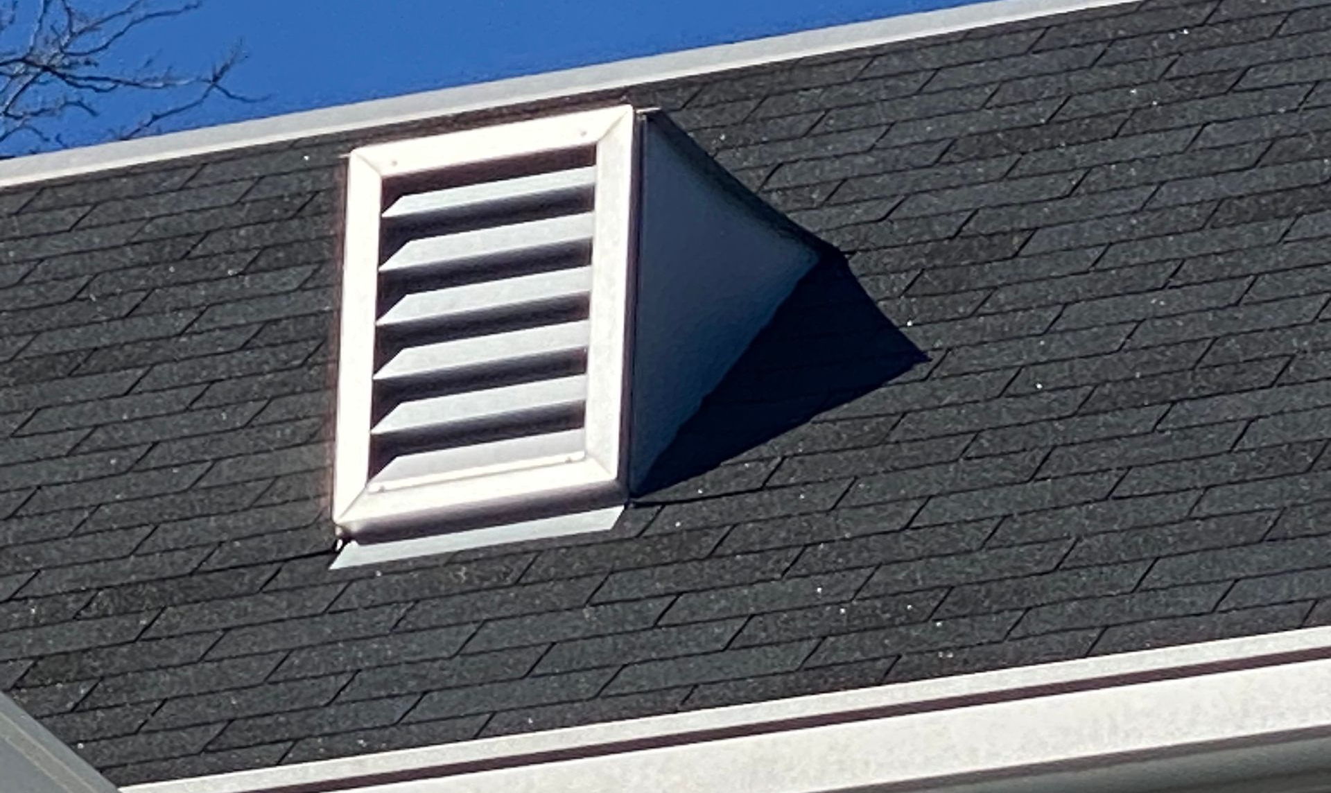 White roof vent on a dark shingled rooftop