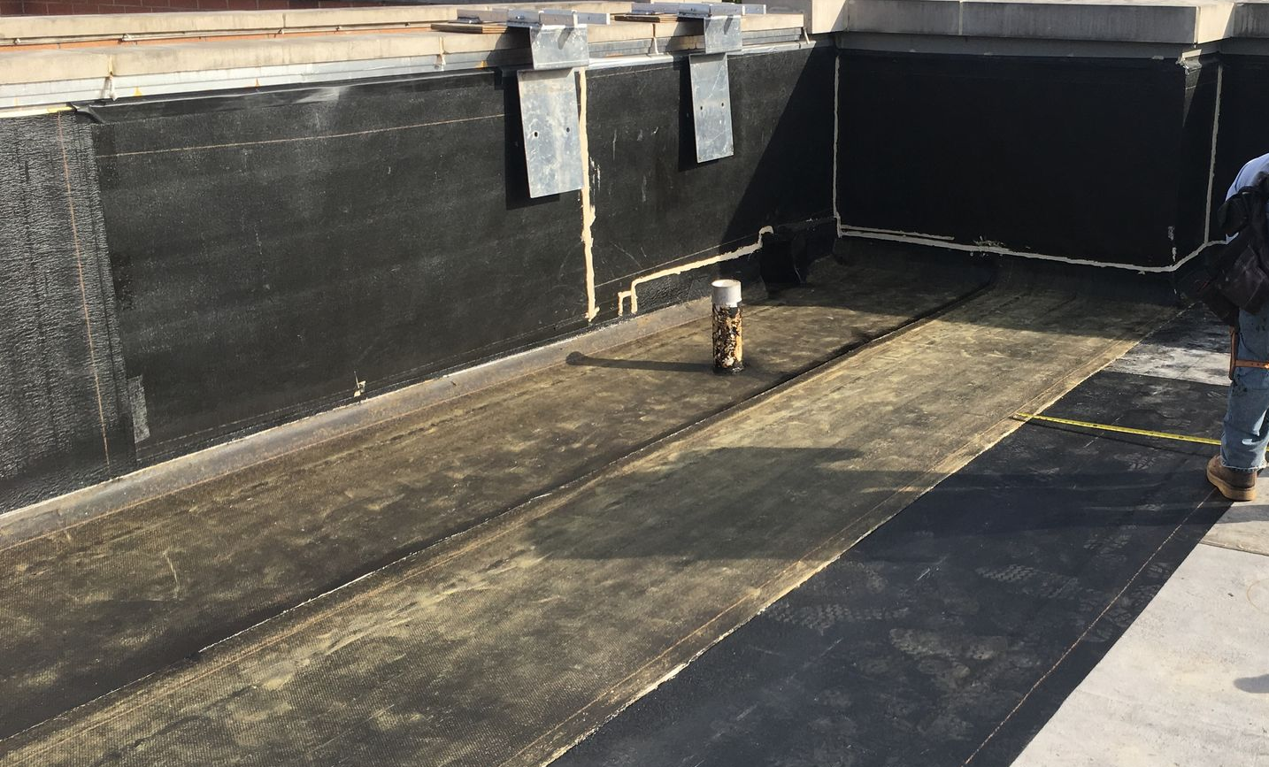Rooftop with black waterproofing and a small vent pipe in the center