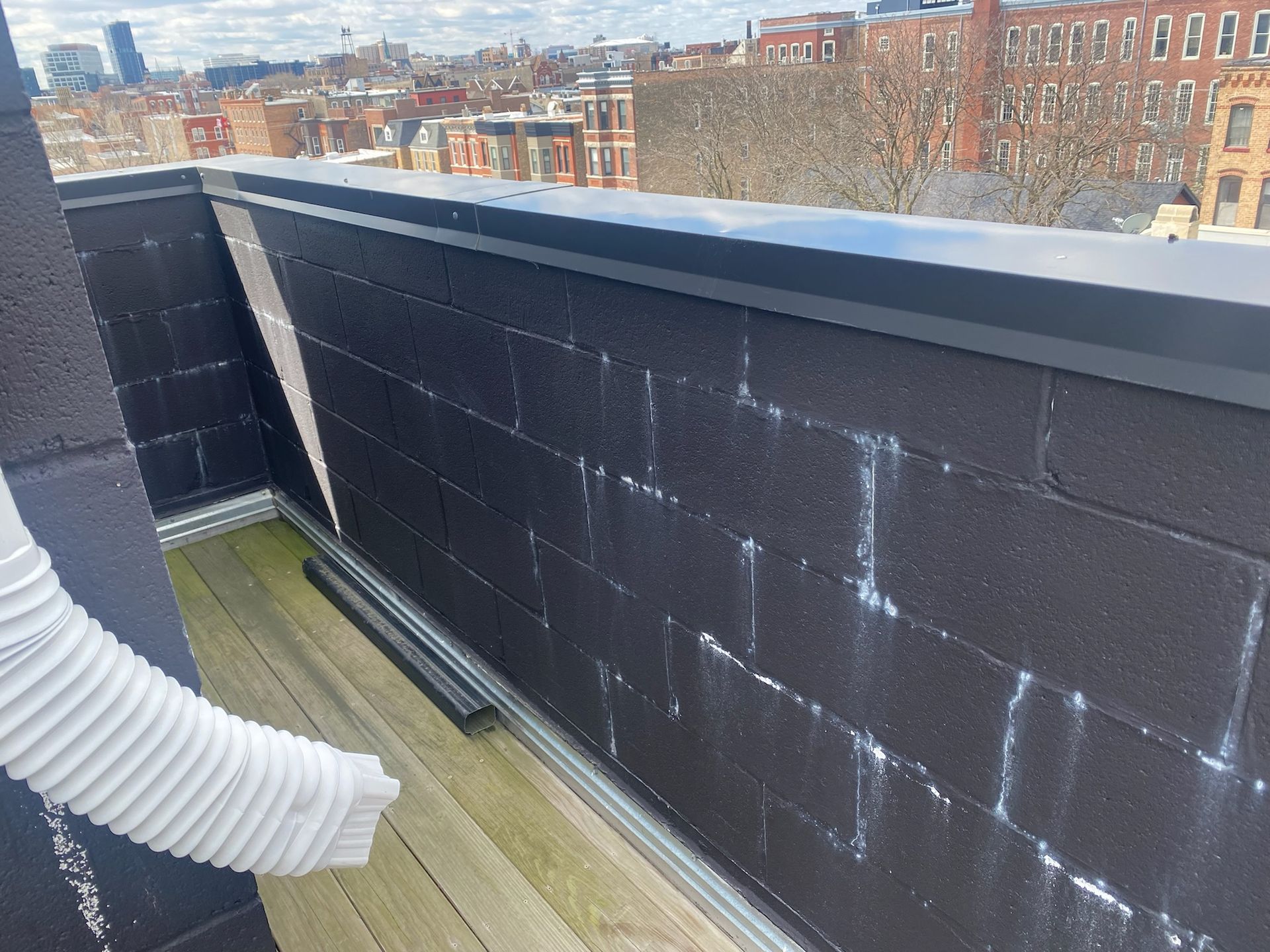 Wet split face block parapet with dark elastomeric paint and a lot of efflorescence.