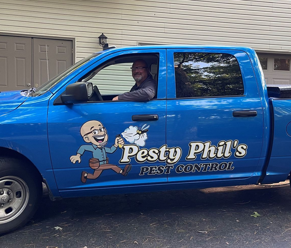 Blue Pesty Phil’s service truck parked in a driveway, with a driver visible through the window.