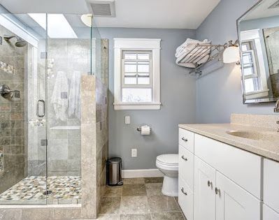 A bathroom with a walk in shower , toilet , sink and mirror.