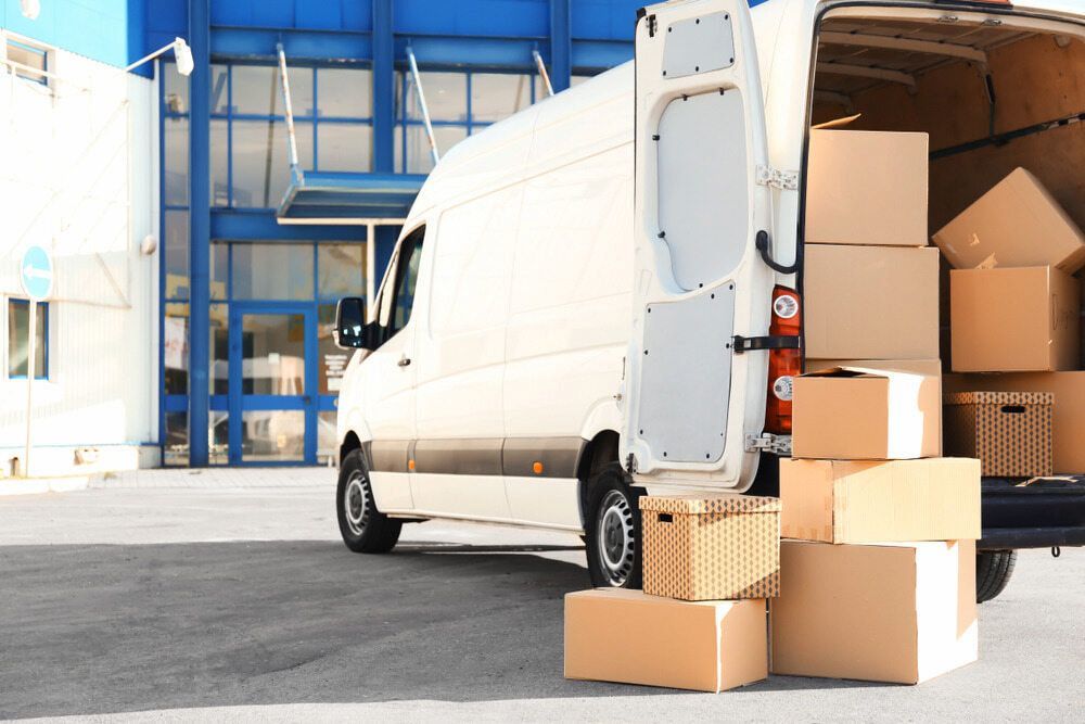 A White Van Is Loaded With Cardboard Boxes In Front Of A Building — Newcastle Moving & Storage in Toronto, NSW