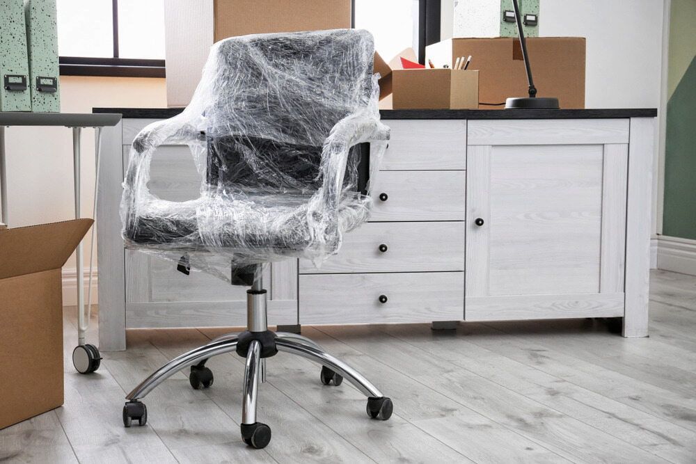 An Office Chair Is Wrapped In Plastic Wrap In A Moving Room — Newcastle Moving & Storage in Salt Ash, NSW