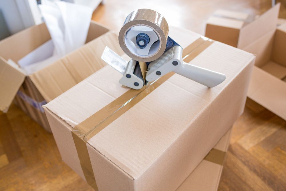 A Tape Dispenser Is Sitting On Top Of A Cardboard Box — Newcastle Moving & Storage in Belmont, NSW