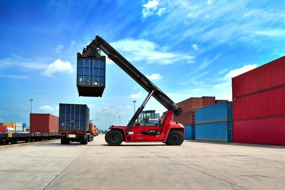 A Red Forklift Is Lifting A Container In A Warehouse — Newcastle Moving & Storage in Salt Ash, NSW