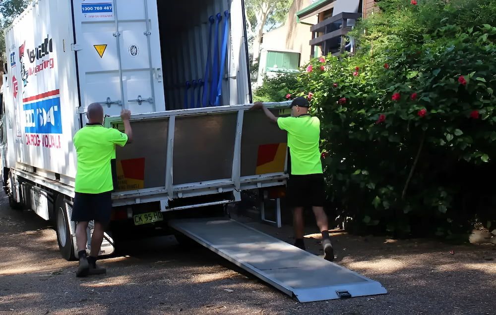 Two Men Are Loading A Container Into A Moving Truck — Newcastle Moving & Storage in Salt Ash, NSW