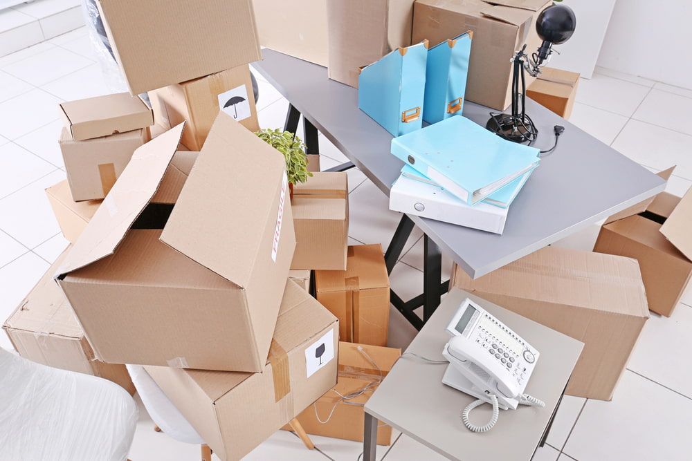 A Pile Of Cardboard Boxes Are Stacked On Top Of A Desk — Newcastle Moving & Storage in Gosford, NSW