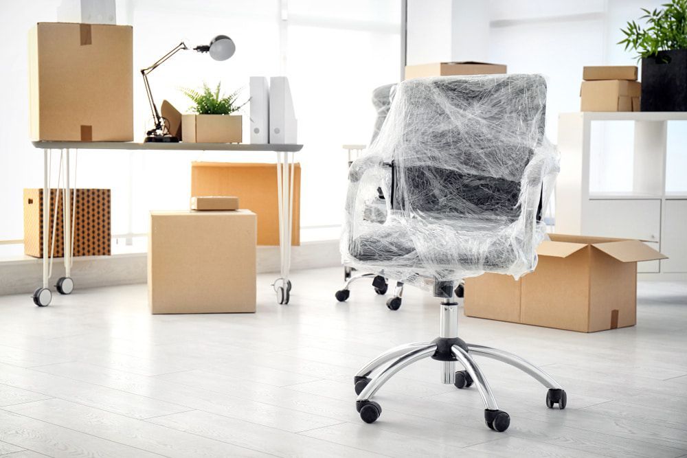 An Office Chair Is Wrapped In Plastic In A Moving Office — Newcastle Moving & Storage in Yarramalong, NSW