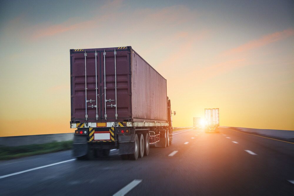 A Semi Truck Is Driving Down A Highway At Sunset — Newcastle Moving & Storage in Salt Ash, NSW