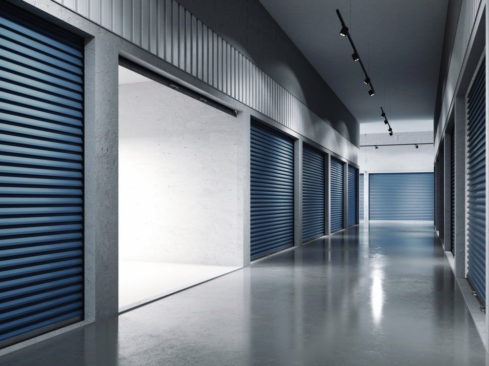 A Hallway Filled With Lots Of Empty Storage Units With Their Doors Open — Newcastle Moving & Storage in Salt Ash, NSW