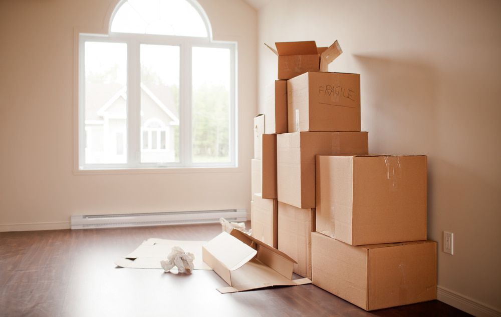 A Bunch Of Cardboard Boxes Are Stacked On Top Of Each Other In An Empty Room — Newcastle Moving & Storage in Toronto, NSW