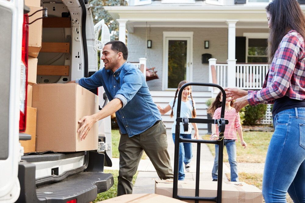 A Family Is Loading Boxes Into A Moving Van — Newcastle Moving & Storage in Toronto, NSW