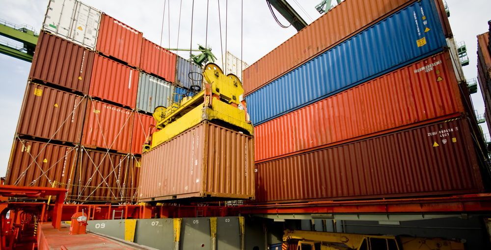 A Stack Of Shipping Containers Being Lifted By A Crane — Newcastle Moving & Storage in Salt Ash, NSW