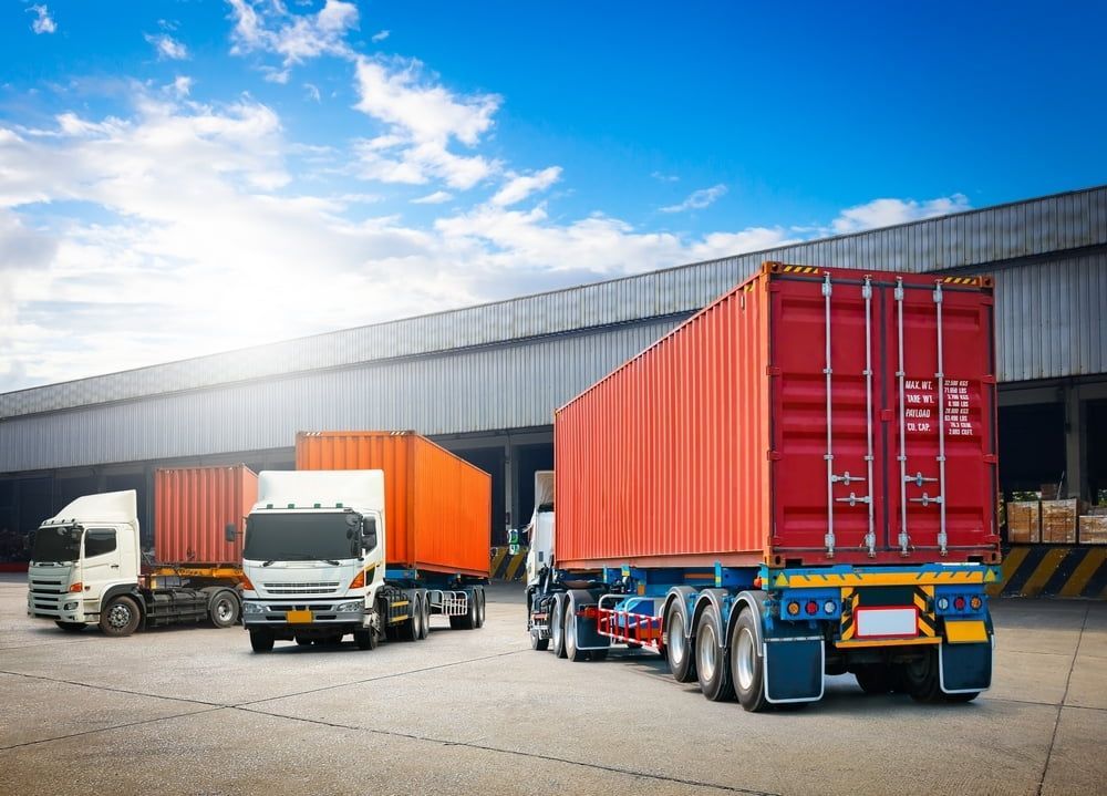 A Row Of Semi Trucks Are Parked In Front Of A Warehouse — Newcastle Moving & Storage in Salt Ash, NSW
