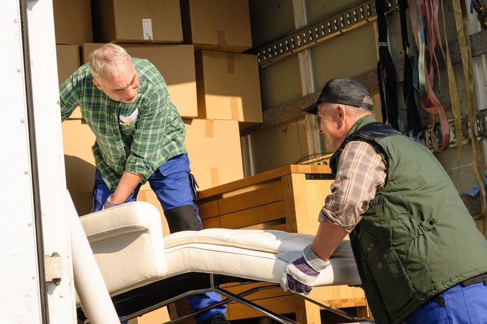 Two Men Are Loading A Couch Into A Truck — Newcastle Moving & Storage in Newcastle, NSW