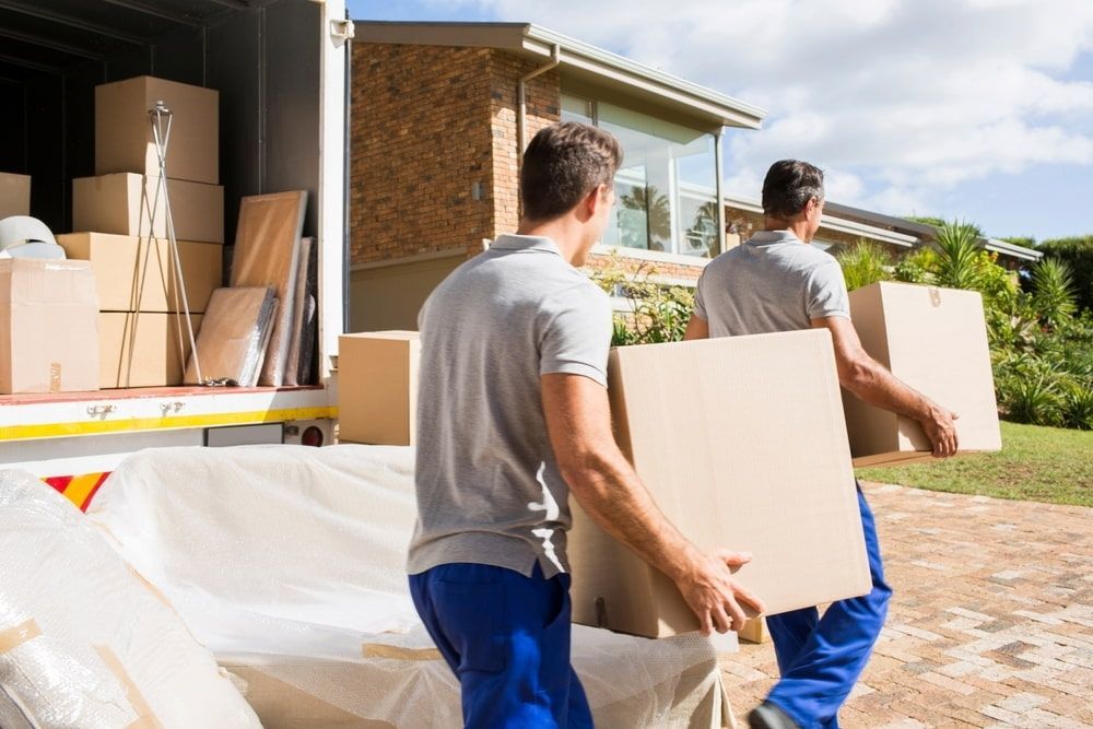 Two Men Are Carrying Boxes Out Of A Moving Truck — Newcastle Moving & Storage in Warnervale, NSW