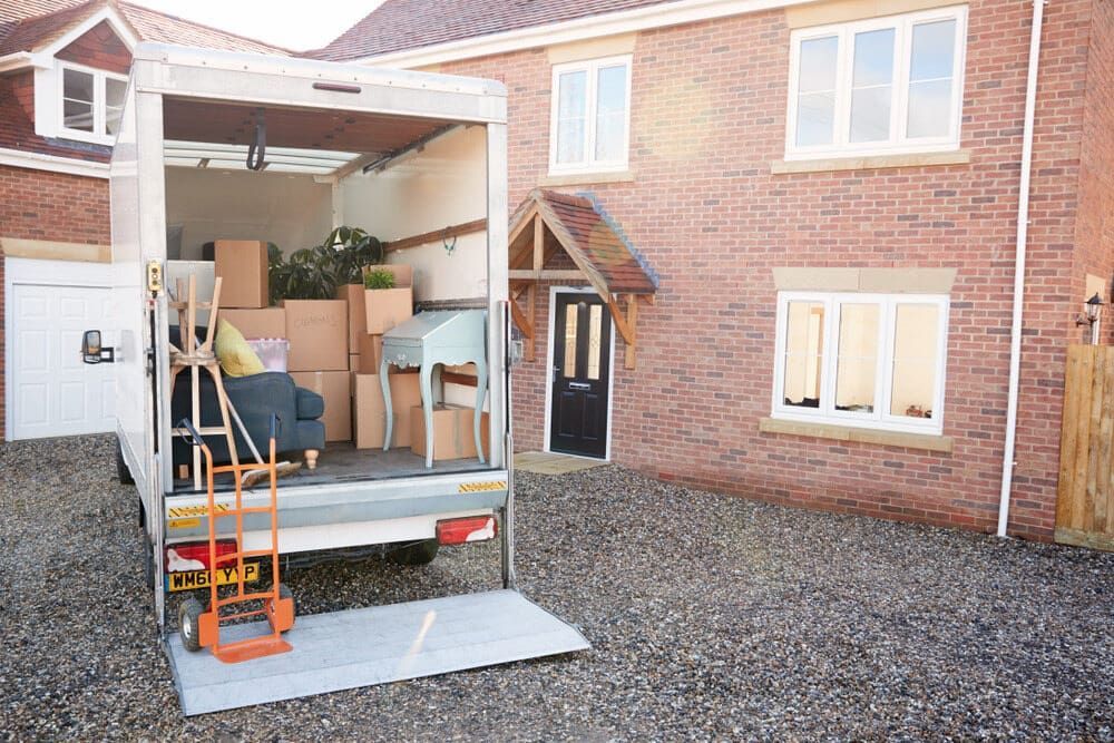A Moving Truck Is Parked In Front Of A Brick House — Newcastle Moving & Storage in Tuggerah, NSW
