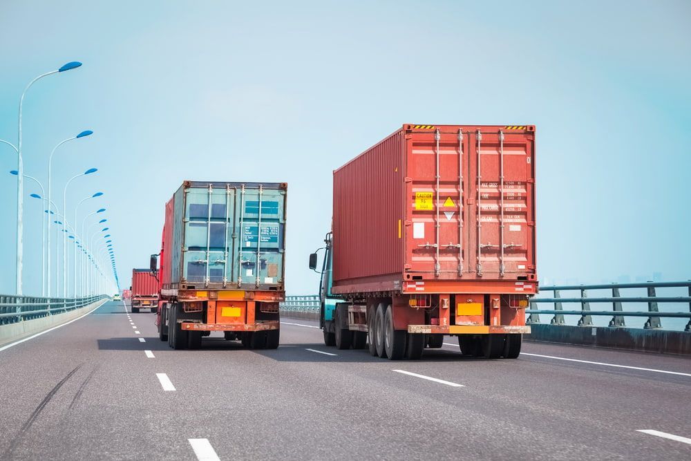 Two Trucks Are Driving Down A Highway Next To Each Other — Newcastle Moving & Storage in Salt Ash, NSW