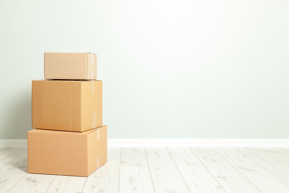 Three Cardboard Boxes Are Stacked On Top Of Each Other In An Empty Room — Newcastle Moving & Storage in Cardiff, NSW