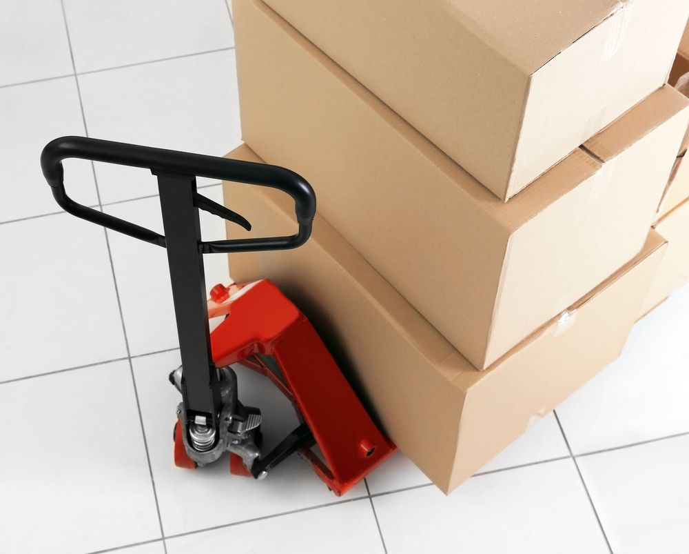A Stack Of Cardboard Boxes Next To A Hand Truck — Newcastle Moving & Storage in Wyong, NSW