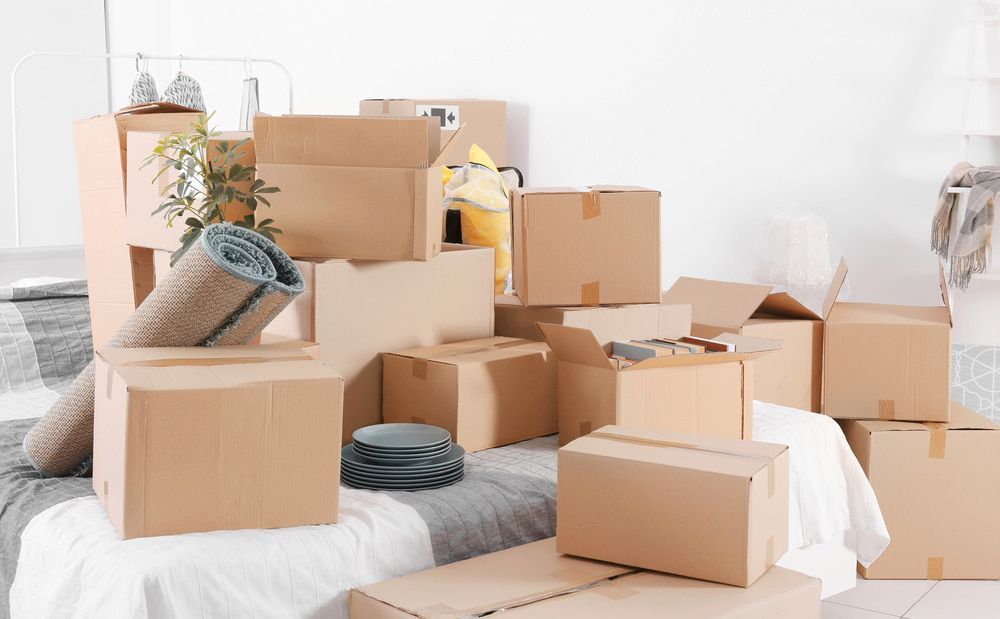 A Pile Of Cardboard Boxes Sitting On Top Of A Bed — Newcastle Moving & Storage in Belmont, NSW