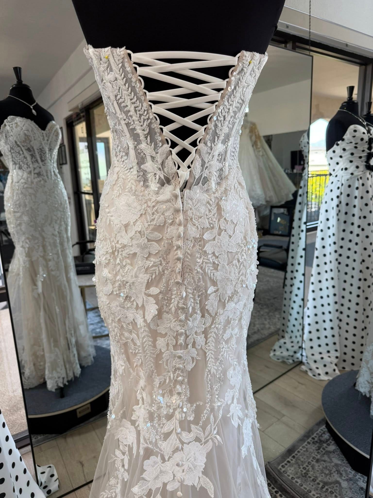 Ivory lace bridal gown on mannequin with crisscross corset back in a dress shop