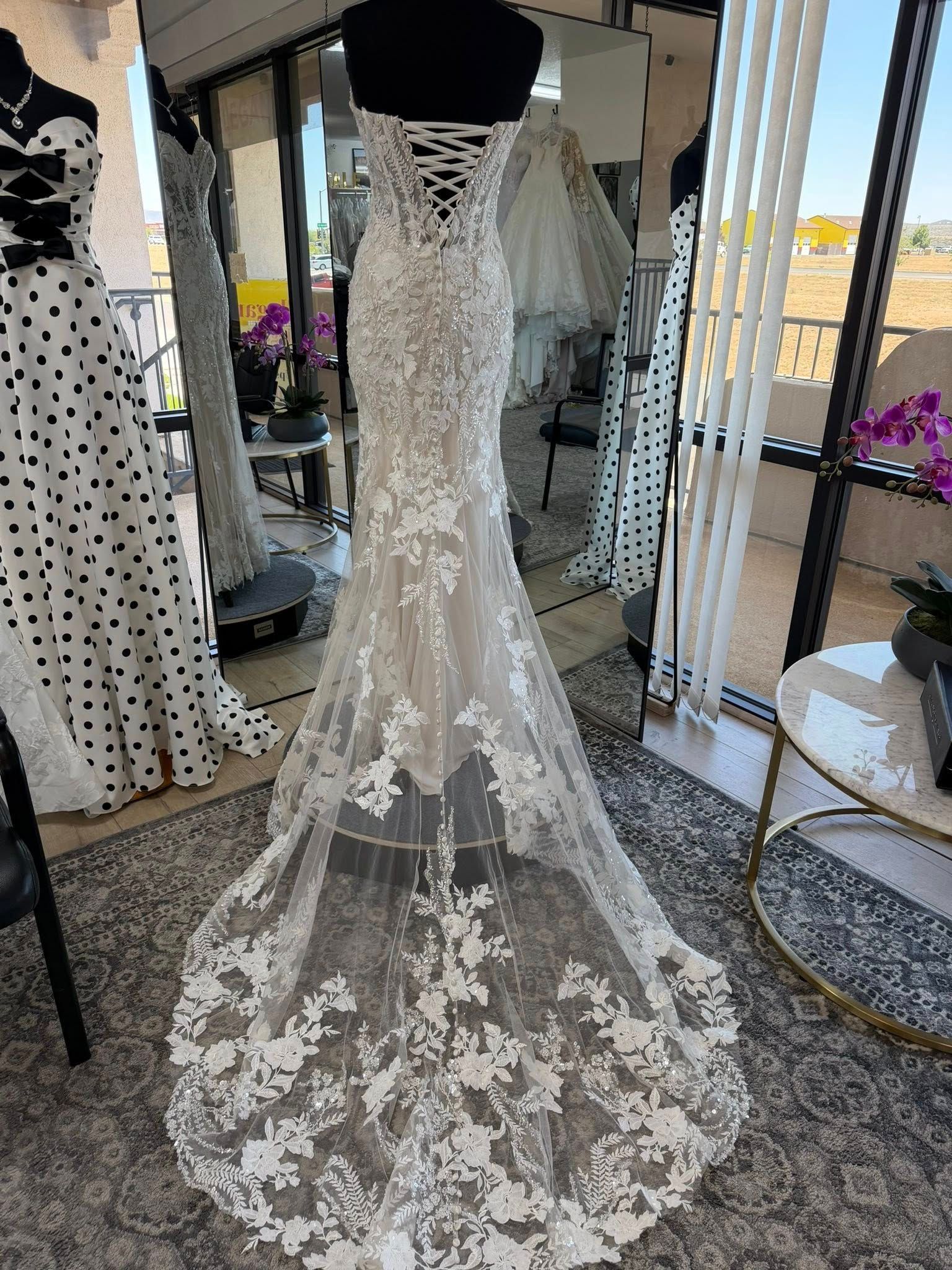 Lace wedding dress on a mannequin, with a long sheer train in a bridal boutique