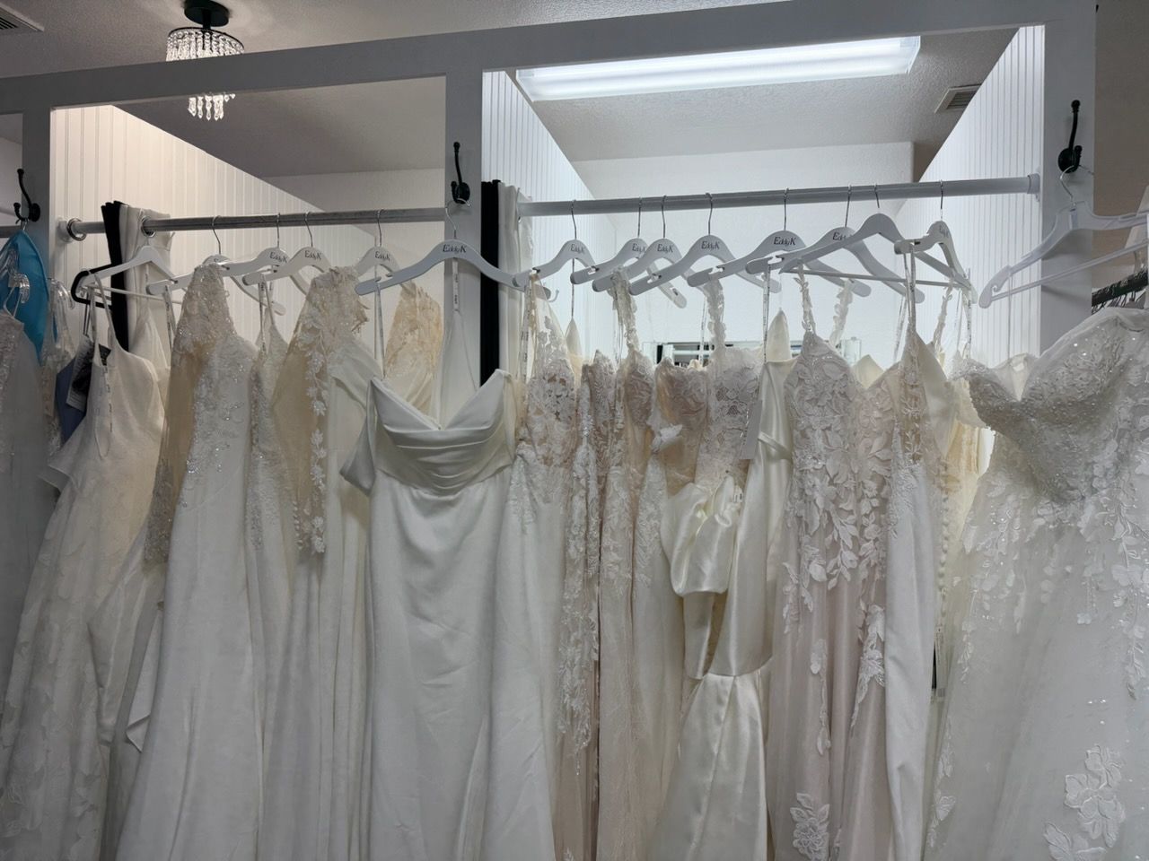Row of white and ivory wedding dresses hanging on a rack in a bridal shop