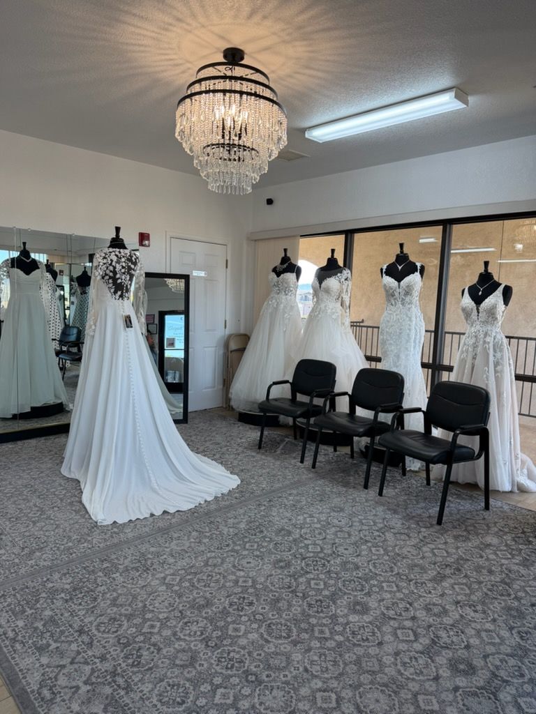 Bridal shop showroom with white wedding gowns displayed on mannequins and a long train dress in the foreground