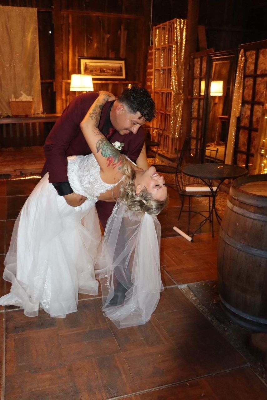 Bride and groom dancing in a warmly lit wood-paneled room, with the bride dipping backward.