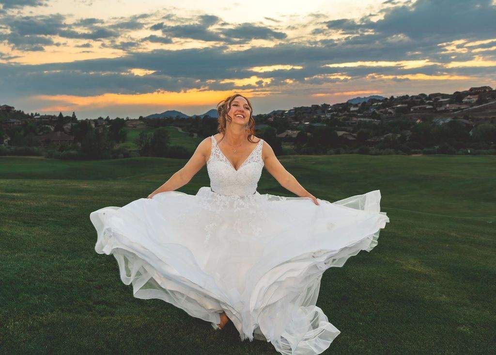 Woman in a white dress twirling on a grassy field at sunset
