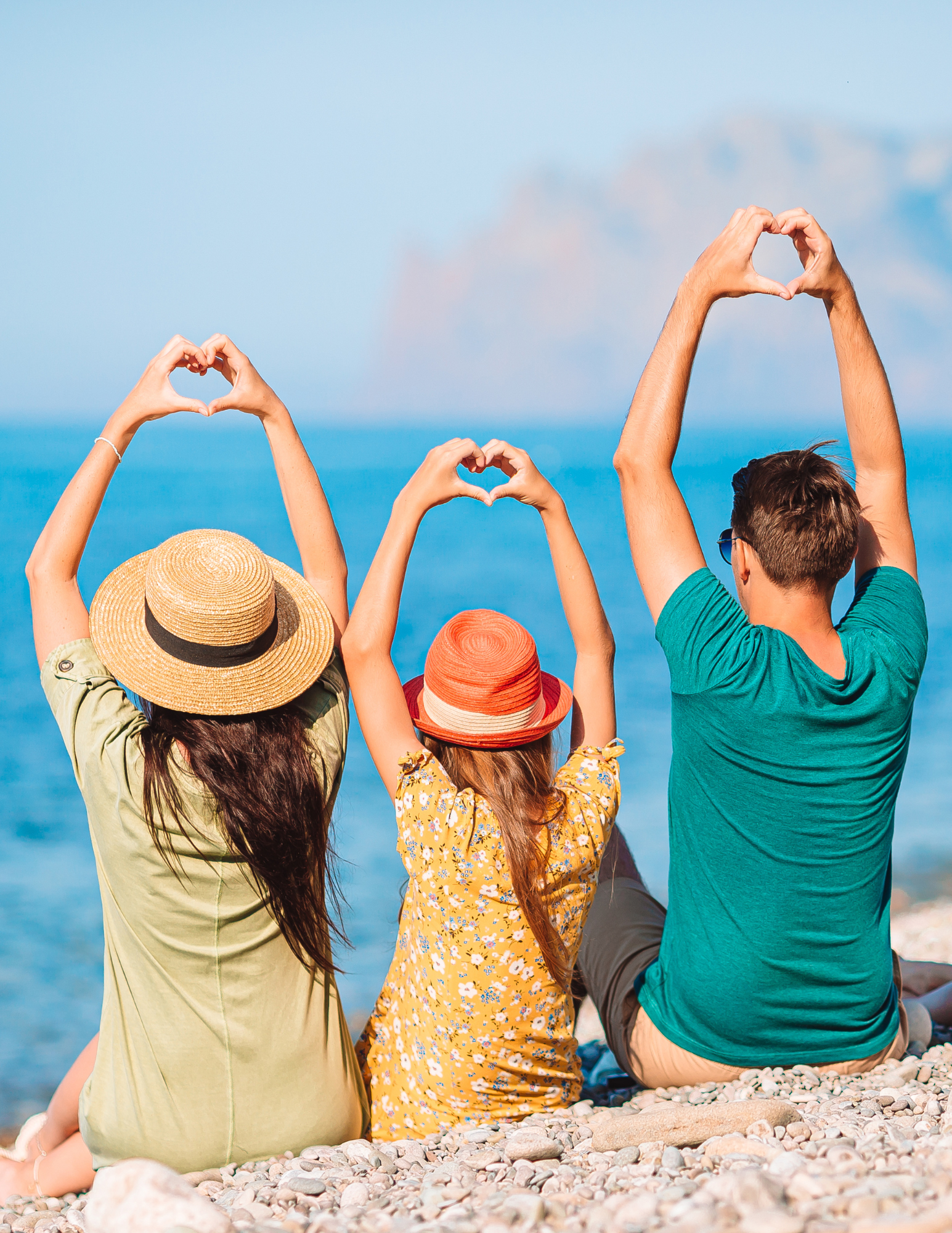 Family on beach making heart shapes with their hands.