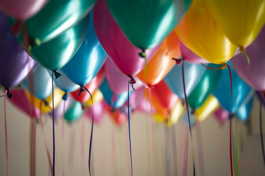 Colorful balloons floating in a room, with ribbons hanging down.