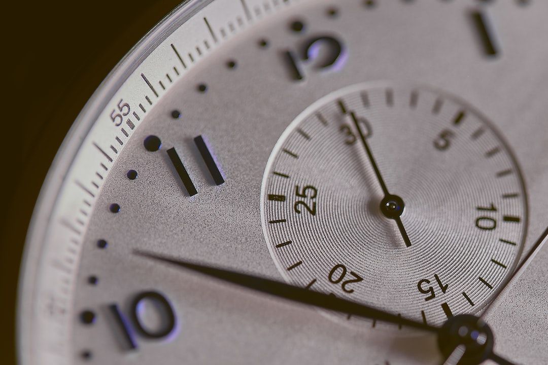 Close-up of a wristwatch face with hour and minute hands, smaller dial, numbers, and tick marks.