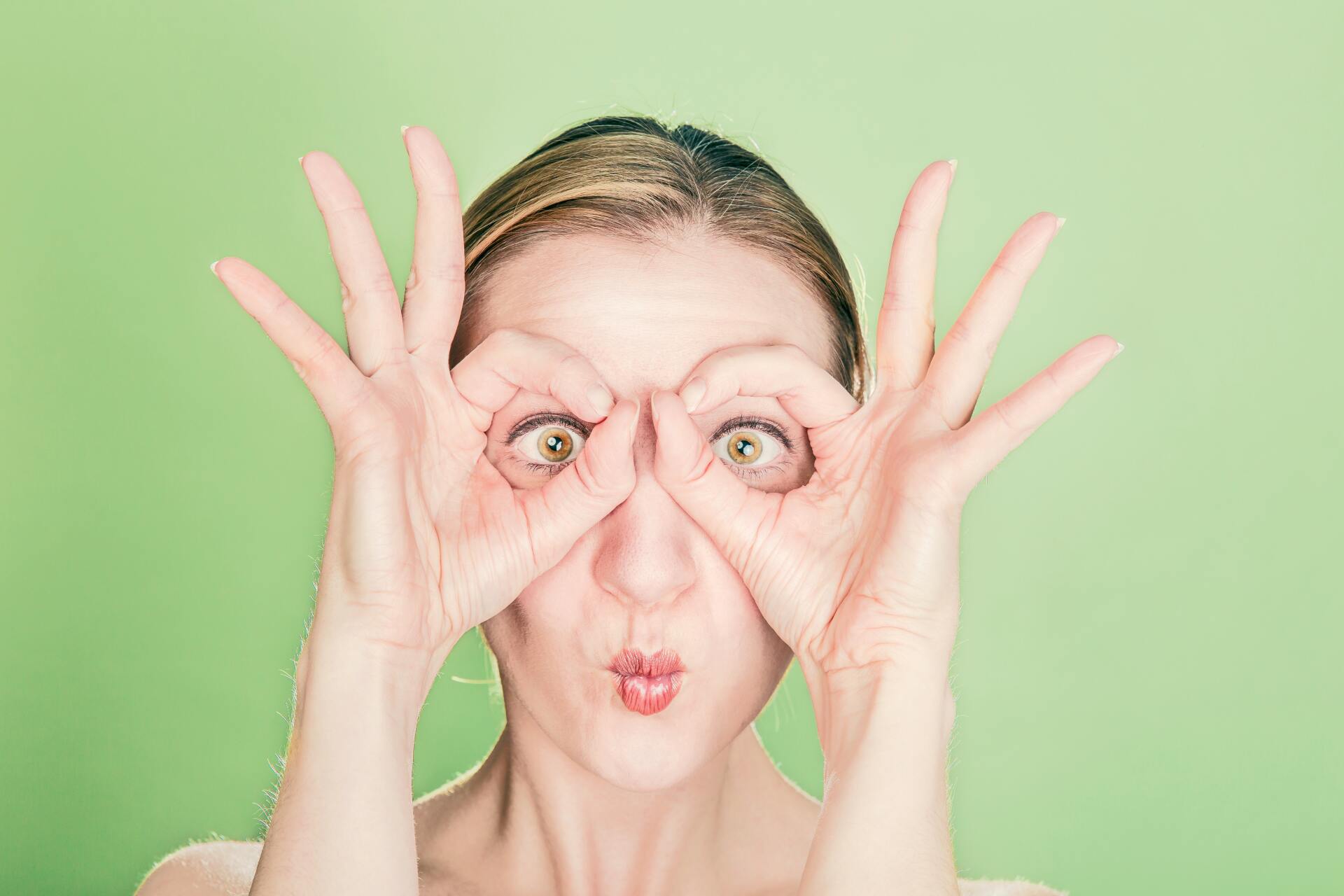 Woman with hands framing eyes, making 