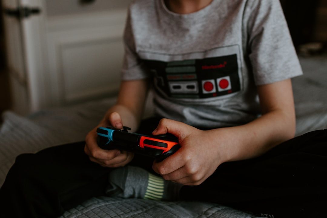 Person sitting on a bed playing a video game with a controller.