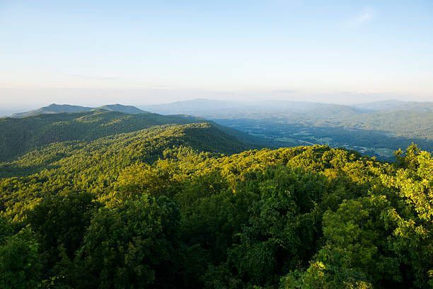 Sunlit green mountain ridges under a hazy blue sky