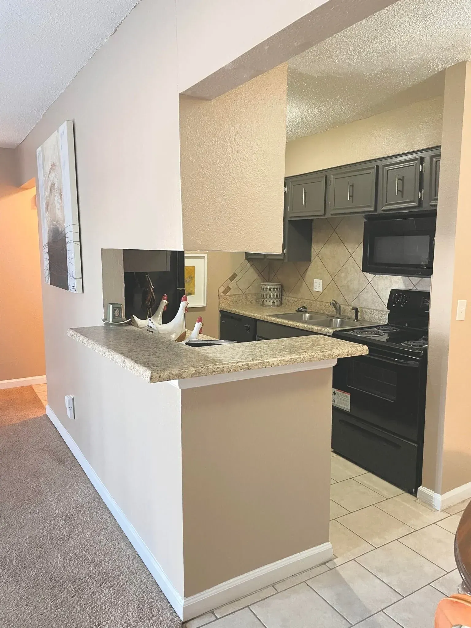 A kitchen and dining space with a breakfast bar, featuring beige paint and dark appliances.