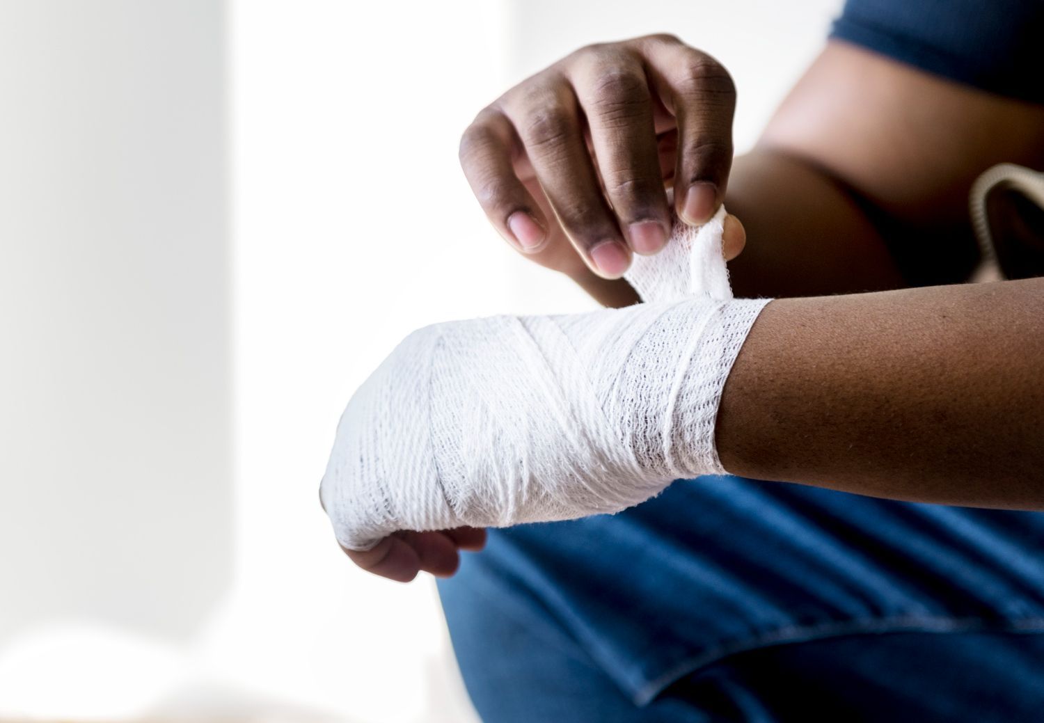 Person wrapping white bandage around wrist.