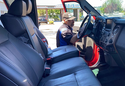 Person seated in a van’s driver area, viewed from the open passenger door, with black leather seats and dashboard visible | Pro-Tech Autoworks