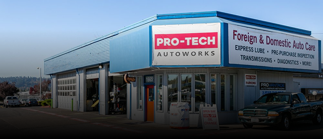 PRO-TECH AutoWorks garage exterior with blue signage and service bays at dusk | Pro-Tech Autoworks