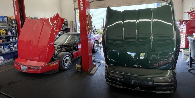 Red and green cars raised on lifts inside an auto repair shop | Pro-Tech Autoworks