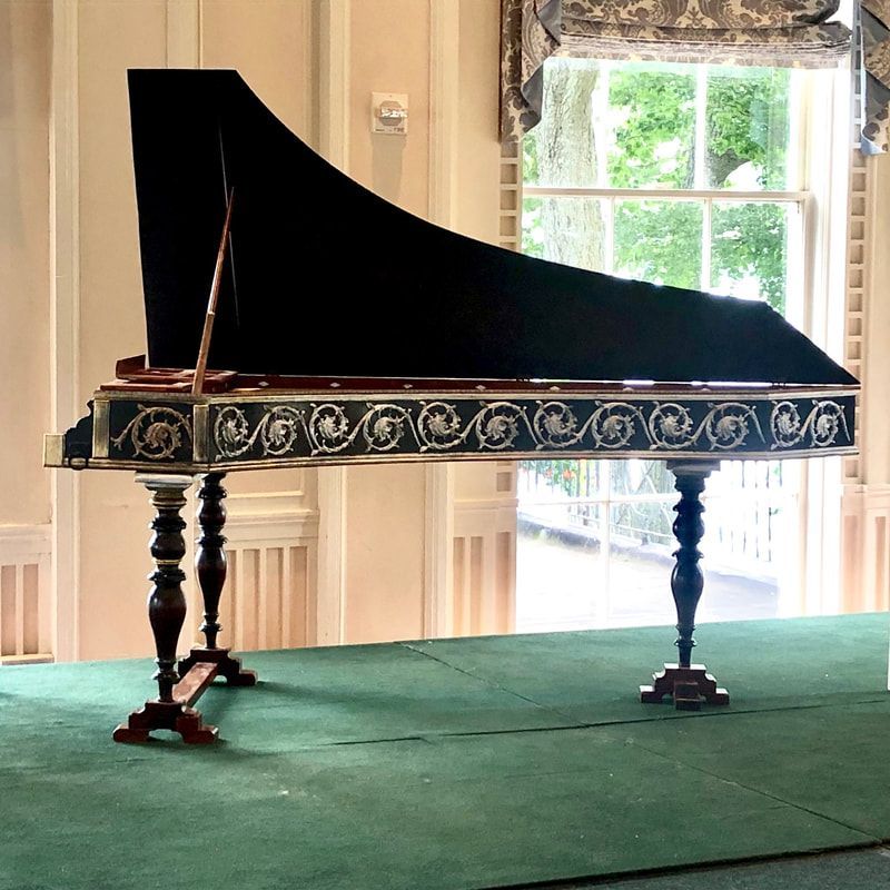A piano is sitting on a green carpet in front of a window
