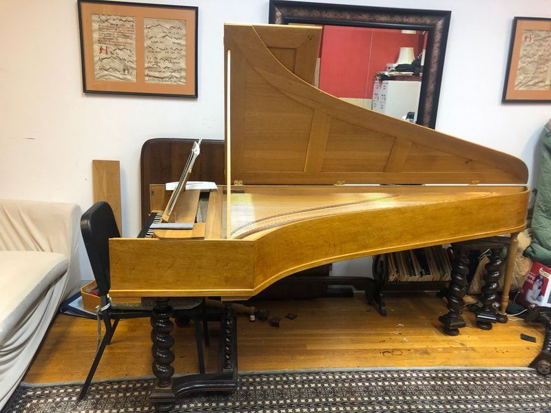 A piano is sitting in a living room next to a chair.