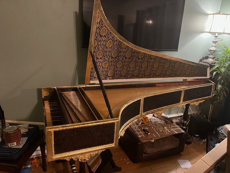 A grand piano is sitting on a wooden floor in a living room.