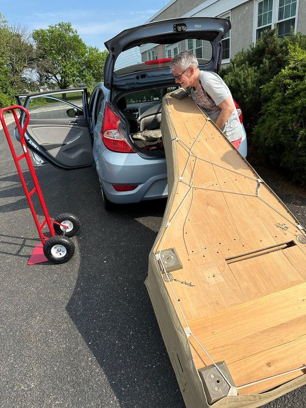 A man is loading a piano into the back of a car.