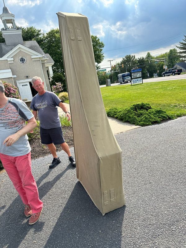 A man and a woman are carrying a large box down a street.