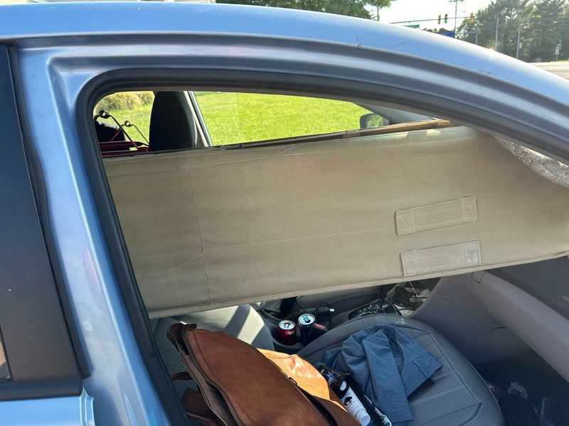 A car with a broken window and a bag in the back seat
